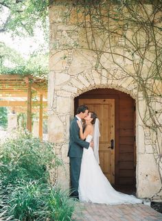 a bride and groom kissing in front of an archway