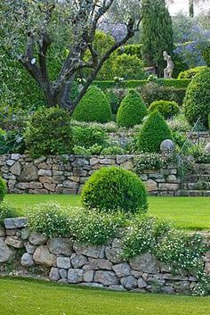 an outdoor garden with stone walls and green grass