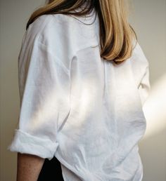 a woman with her back turned to the camera, wearing a white shirt and black pants