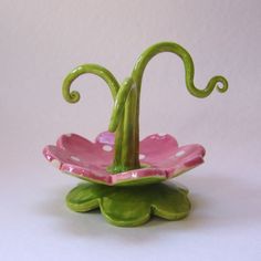 a green and pink flower shaped vase on top of a white surface with polka dots