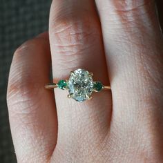 a woman's hand with a diamond and emerald ring