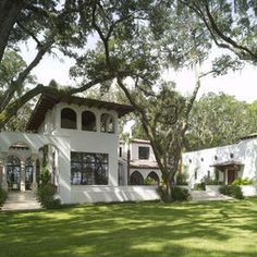 a large white house surrounded by trees and grass