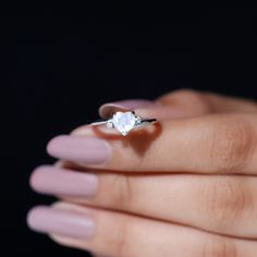 a woman's hand holding an engagement ring with a white diamond on the middle