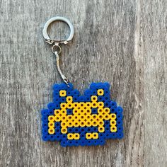 a keychain made out of legos is shown on a wooden surface with a blue and yellow object in the middle