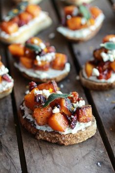 small appetizers with fruit and cheese on them are sitting on a wooden table