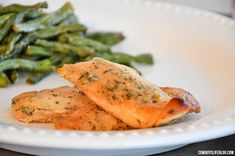 a white plate topped with fish and asparagus next to a side of green beans