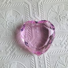 a pink heart shaped object sitting on top of a white tablecloth covered wallpaper