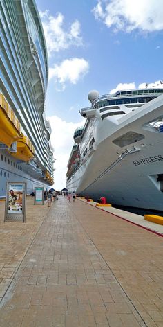 two cruise ships are docked in the water next to each other on brick walkways