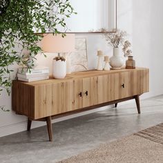 a wooden sideboard with drawers and vases on it