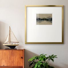 there is a small sailboat on the shelf next to a potted green plant