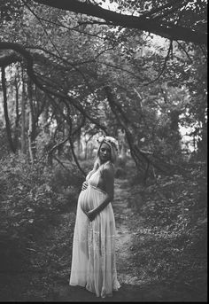 a pregnant woman is standing in the woods