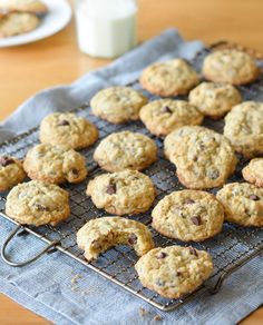 chocolate chip cookies cooling on a wire rack next to a glass of milk and a bottle of milk