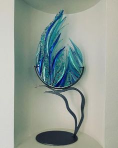 a blue glass sculpture sitting on top of a white shelf next to a wall mounted mirror