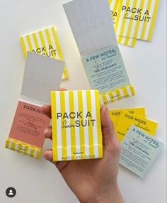 a person holding up some yellow and white business cards with the words packa & sut on them