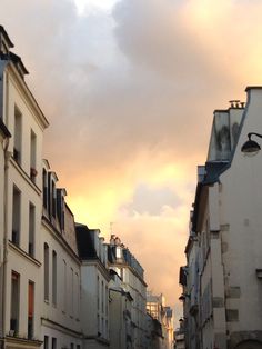 the sky is very cloudy and there are people walking on the sidewalk in front of some buildings