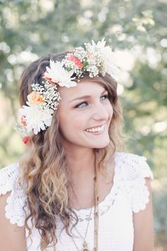 a woman with flowers in her hair smiles at the camera while wearing a flower crown