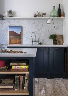 a kitchen with marble counter tops and blue cabinets, along with books on the shelves