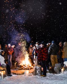 a group of people standing around a fire in the snow