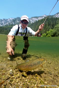 a man standing in the water with a fish on his feet and holding a fishing rod