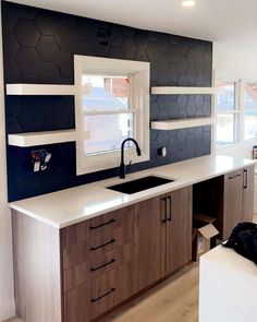 a kitchen with white counter tops and black backsplashing on the wall behind it