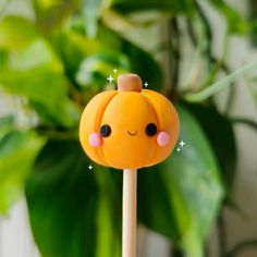 a close up of a cake on a stick near a potted plant with leaves in the background