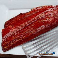 a large piece of meat sitting on top of a white plate next to a spatula