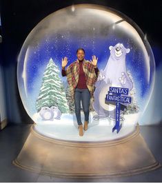 a man standing in front of a snow globe with the words santa's fantastic written on it