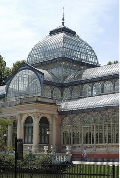 a large glass building with lots of windows on it's sides and a black fence around it