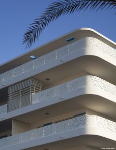 a tall white building with balconies on top