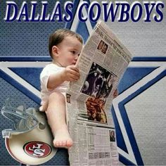 a baby sitting on top of a football helmet and reading a newspaper with the word cowboys in it