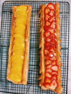 two pieces of food sitting on top of a cooling rack with strawberries and cheese