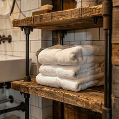 towels stacked on top of wooden shelves in a bathroom