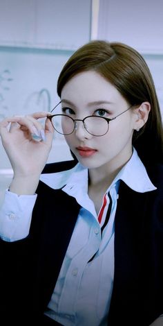 a woman wearing glasses is posing for the camera with her hand on her eyeglasses