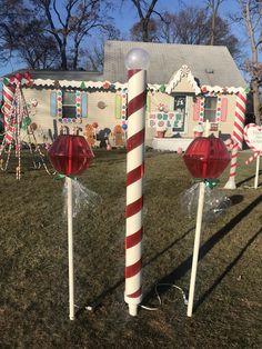 two candy canes in front of a house decorated for christmas