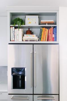 a stainless steel refrigerator freezer sitting in front of a book shelf filled with books