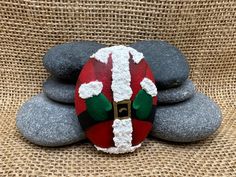 a rock with a santa clause hat on it sitting next to some black and white rocks