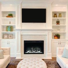 a living room filled with white furniture and a flat screen tv mounted above the fireplace