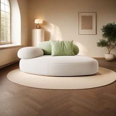 a white round couch sitting on top of a wooden floor next to a potted plant