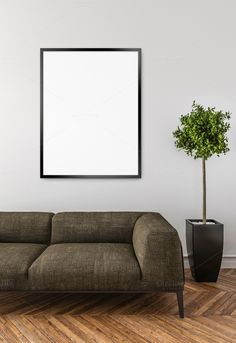 a living room with a couch, plant and large poster hanging on the wall above it