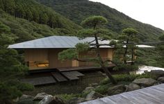 a house on the side of a mountain with trees and rocks in front of it