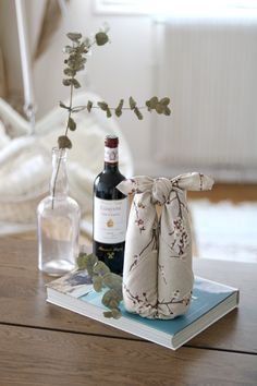 a bottle of wine sitting on top of a table next to a vase with flowers