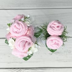 pink and white flowers are arranged on a wooden surface with greenery in the center