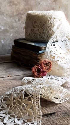 two pieces of lace sitting on top of a wooden table next to a book and flower