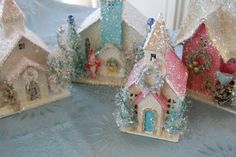 three small houses with trees and snow on the roof are shown in front of each other