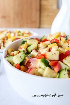 a bowl filled with chopped vegetables on top of a white table next to another bowl