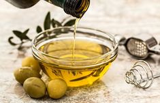 a glass bowl filled with olives and oil