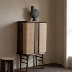 a tall cabinet sitting next to a window in a room with wooden floors and walls