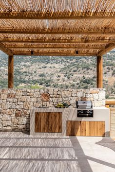 an outdoor kitchen and grill area with stone walls