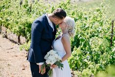 a bride and groom kissing in the vineyard