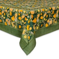 a green table cloth with yellow flowers and leaves on the top, sitting on a white surface